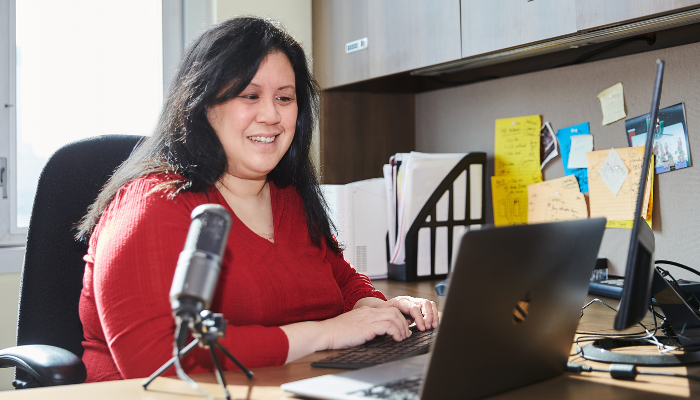 Teresa Chan sitting at a desk in front of a computer and microphone